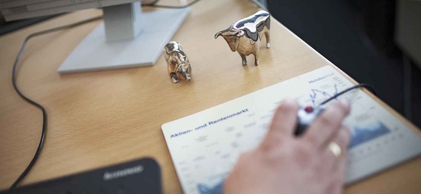 Schreibtisch mit Metallfigur Stier und Bär, dazu Mousepad mit Börsenkursen